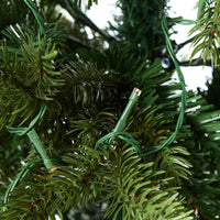 A close-up of a branch from the Celeste Pencil Pine Christmas Tree 180cm highlights its slender design, beautifully adorned with green string lights featuring 220 LED bulbs, creating a festive glow.