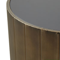 The Lola Drum Side Table 42x42x45cm features a dark glass top and a bronze-hued, vertically grooved powder-coated metal base—an elegant accent piece for any space.