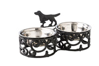 The Double Dog Bowl 35x17cm set includes two stainless steel bowls in a sturdy iron stand, beautifully finished in antique black and silver, with an adorable dog-shaped decoration.