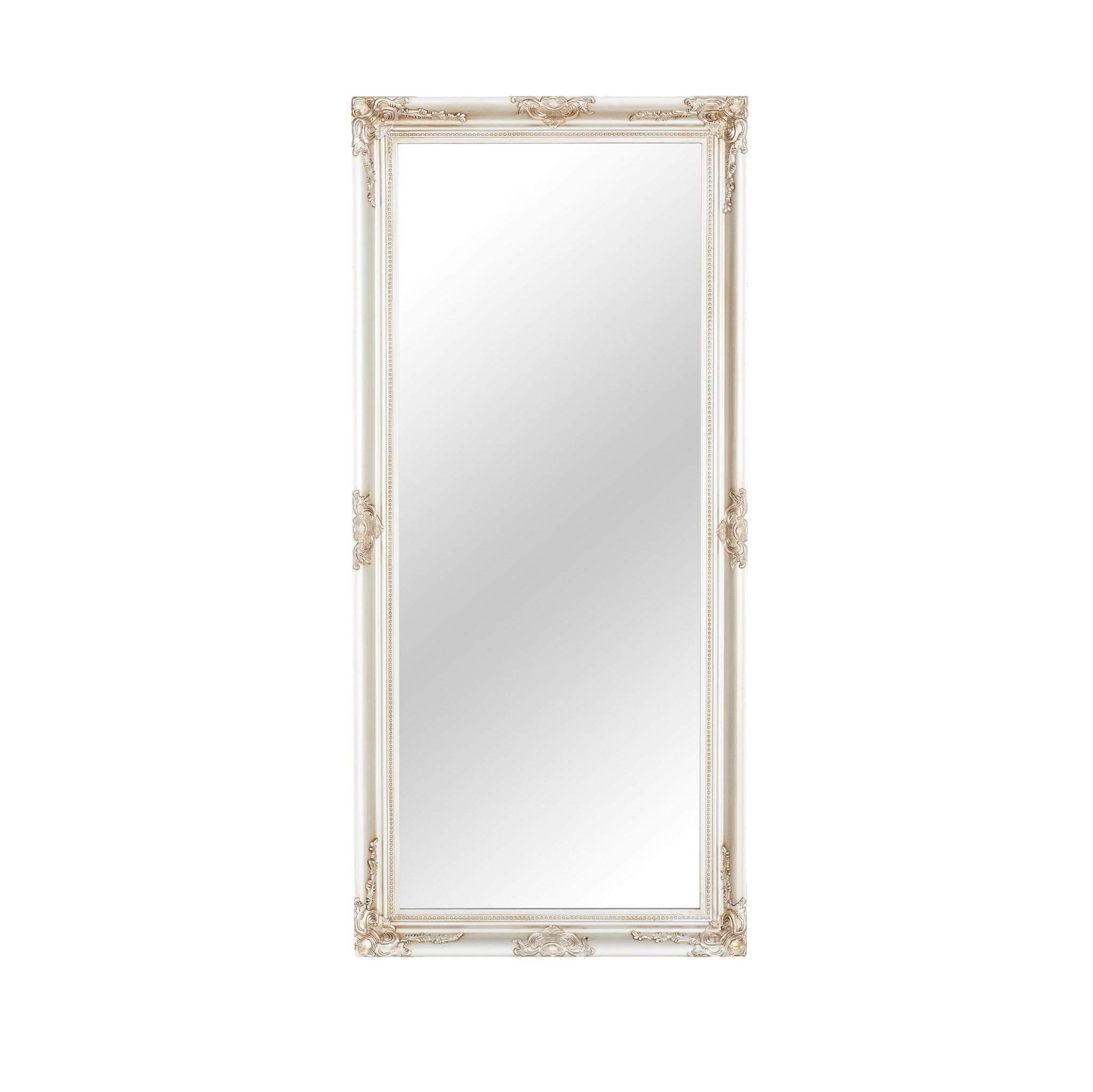The Jane Mirror Champagne Silver 167x77cm features a tall rectangular shape with an ornate frame adorned with intricate carvings at the corners and edges, showcasing a versatile design. This elegant mirror seamlessly complements any decor setting, exuding a timeless charm.