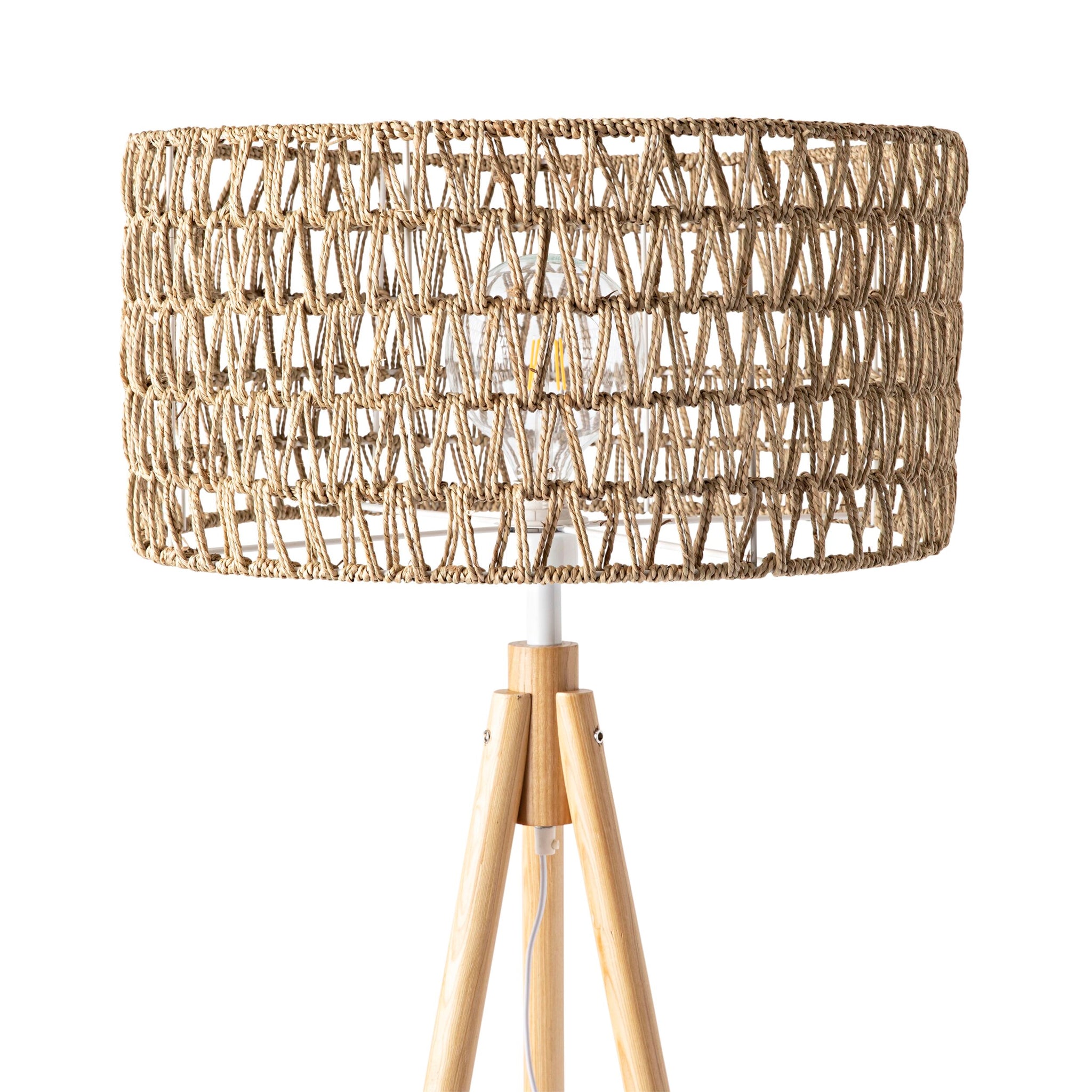 The Lexi Seagrass Natural Tripod Floor Lamp (165x45cm) features a woven rattan drum shade and wooden tripod legs, inspired by coastal living, shown against a white background.