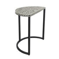 The Bone Inlay Half Moon Side Table features a black and white design with a patterned top and sleek metal legs, reminiscent of an elegant bone inlay side table.