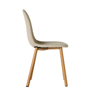 The Knox Dining Chair Stone offers a side view of a modern design with an upholstered bucket seat and backrest in beige boucle fabric, complemented by wooden legs—perfect for a coastal home.