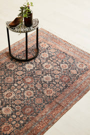 A patterned rug with a small table and plant on it