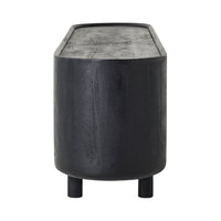 A cylindrical dark wood side table with a black sandblasted finish, two short legs, and a subtly textured flat surface complements the Aurora Entertainment Unit Black for cohesive media storage.