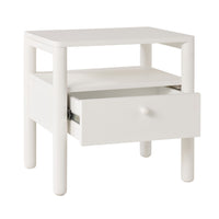 The Spintara 1 Drawer Bedside Table White features rounded legs, an open shelf, and a single drawer, adding a touch of coastal country style to any bedroom.