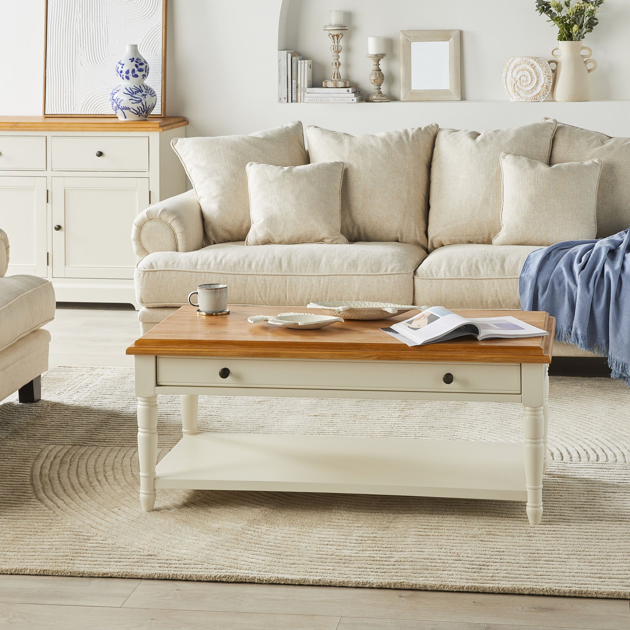 Close-up of white coffee table showing the wood top, single drawer front, and knob detail.