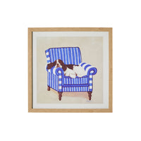 The Springer On Blue Framed Print 40x40cm by Carol Dillon features a vibrant depiction of a Springer Spaniel lounging gracefully on a blue and white striped armchair in an elegant wooden frame.