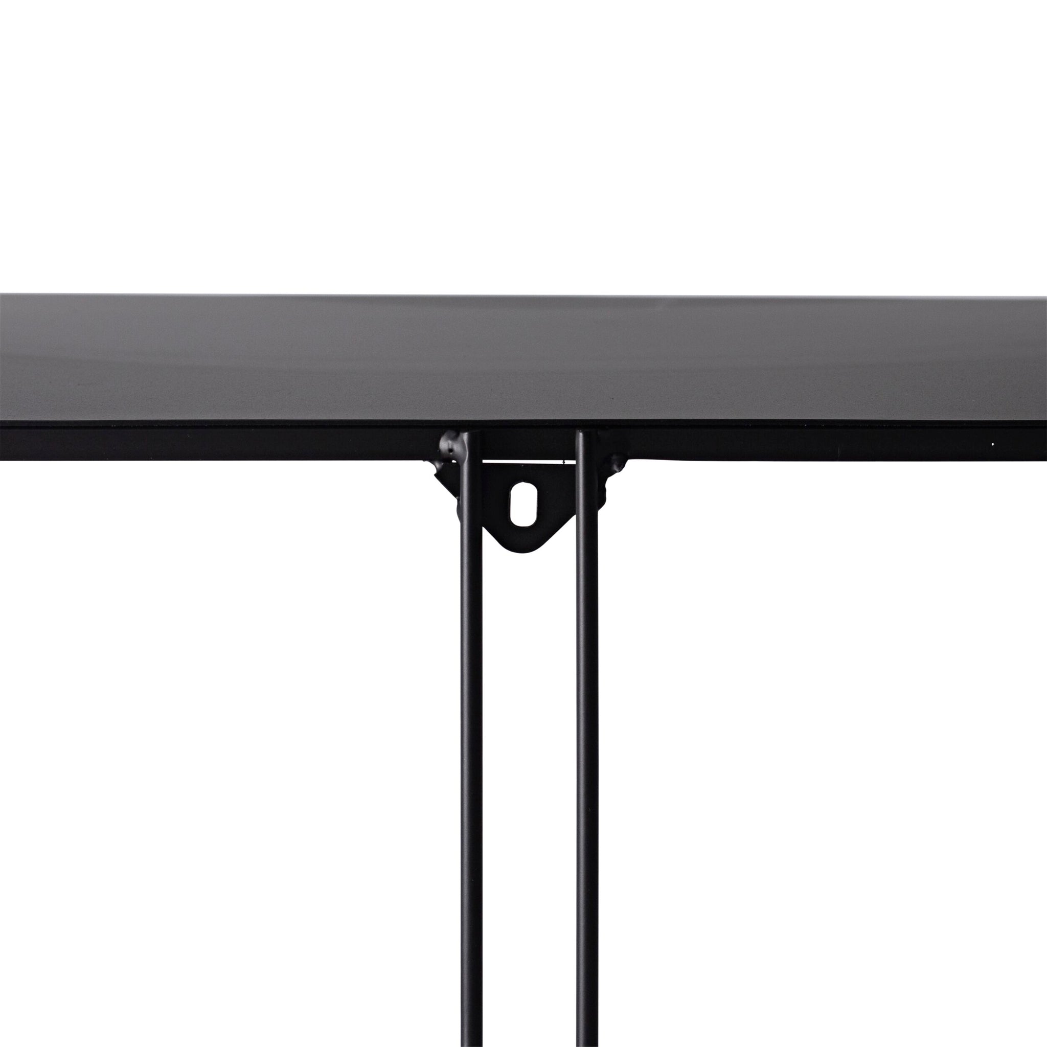 A close-up of the edge of a black tabletop supported by two thin, powder-coated iron legs is reminiscent of the minimalist design found in the Hendrix 5 Tier Tall Shelving Unit (182.5 x 60cm).