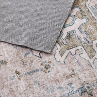 Close-up of the Manisa Washable Rug 240x300cm, featuring a grey textured cloth on a Persian-inspired rug with faded pastel colors and geometric patterns, crafted from durable, machine-washable polyester for easy care.