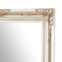 A close-up of a corner of the Jane Mirror Champagne Silver 167x77cm reveals its ornate, antique-style gold frame with intricate detailing on a plain reflective surface, highlighting its champagne silver mirror finish.