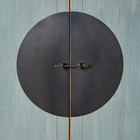 A large round metal door handle with a keyhole graces the weathered dove grey surface of the Sansha Wedding Cabinet, hinting at Chinese antique style.