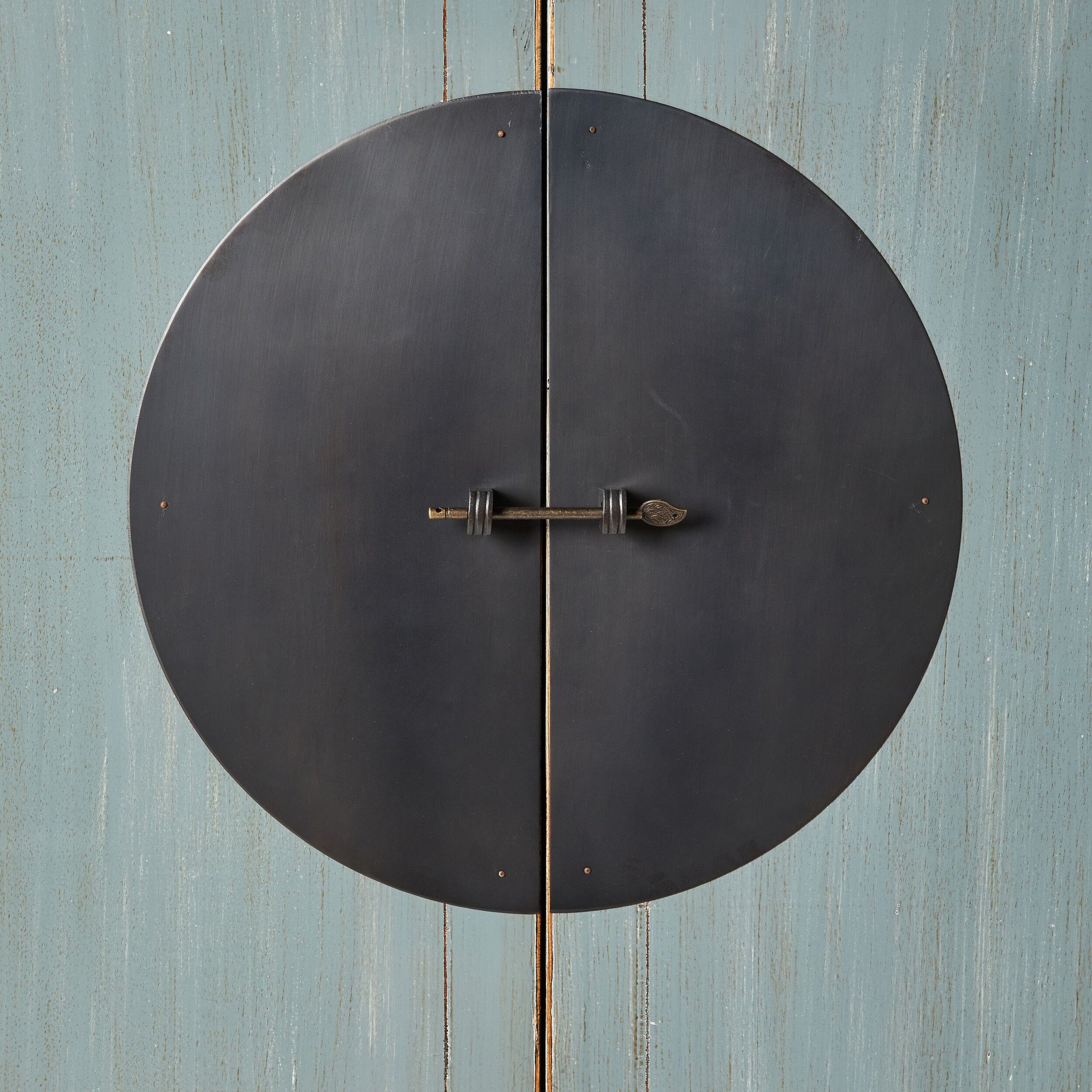 A large round metal door handle with a keyhole graces the weathered dove grey surface of the Sansha Wedding Cabinet, hinting at Chinese antique style.