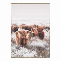 The "Scottish Highland Cow Herd Framed Print 140x100cm" captures a majestic cow with impressive horns standing in a frosty, grassy field under a gray sky, conveying the essence of rustic décor.
