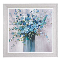 A framed print of a blue floral bouquet in a tall vase, echoing the Arthouse Sea Isle Wildflowers design, set against a muted background and enclosed in light gray wood.