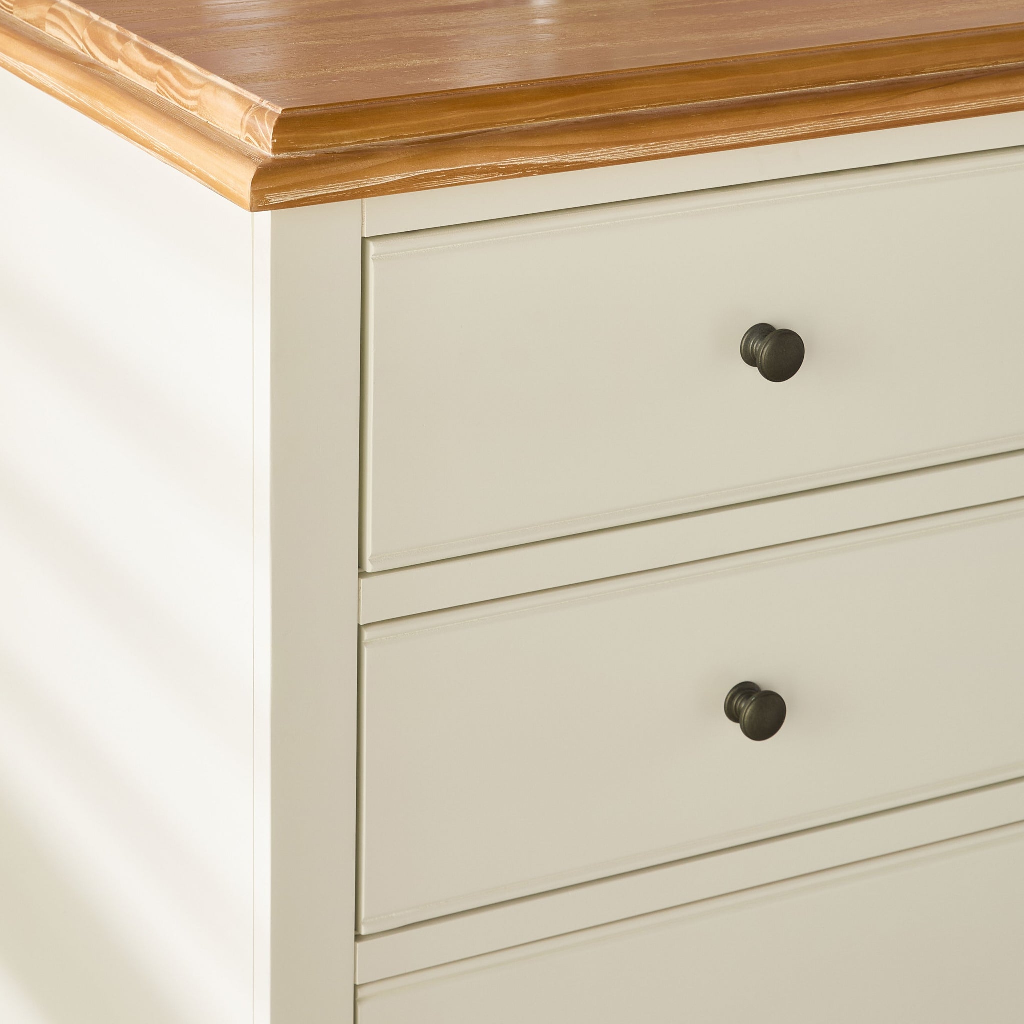 End view of dresser with wooden top and silver knobs, from a slight angle.